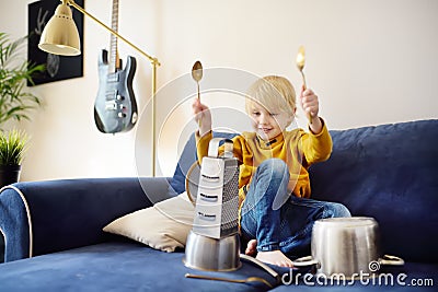 Mischievous preschooler boy play the music using kitchen tools and utensils. Funny drum part from little boy Stock Photo