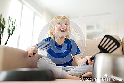 Mischievous preschooler boy play the music using kitchen tools and utensils at home during quarantine. Funny drum part from child Stock Photo