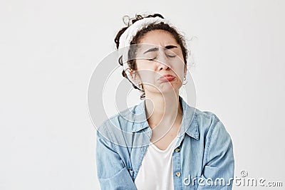 Miserable upset gloomy female with dark and wavy hair looks offended, pouts lips, frowns face in dispair, frustrated Stock Photo