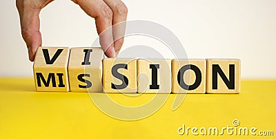 Mission vision symbol. Businessman hand turns wooden cubes and changes the word `mission` to `vision`. Beautiful yellow table, Stock Photo