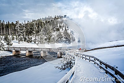 Mist from hot geisers flows over snowy bridge Stock Photo