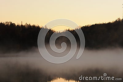 Mist over the lake, dusk over the lake, a very dense fog, dawn, blue sky over the lake, the morning comes, the forest Stock Photo