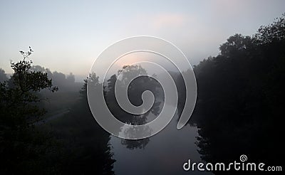Mist at the river and a forest in silhouette. Stock Photo