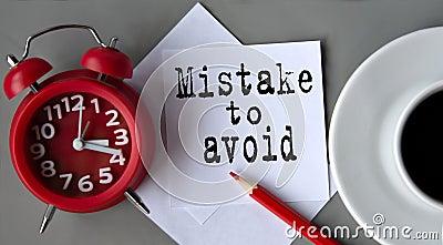 MISTAKE TO AVOID - words on white paper on the background of an alarm clock, a pencil and a cup of coffee Stock Photo