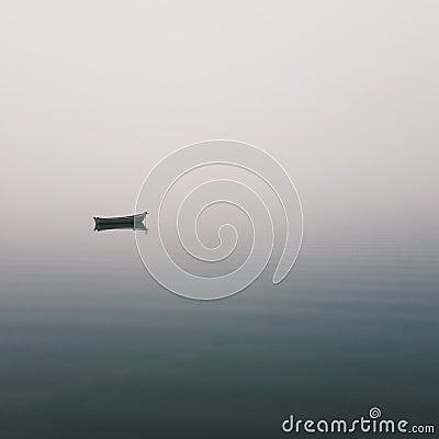 Mistic lonely boat in the middle of the lake, mist fog Stock Photo