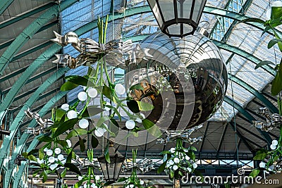 Mistletoe Christmas lights and a giant silver bauble hanging in Covent Garden, London Editorial Stock Photo