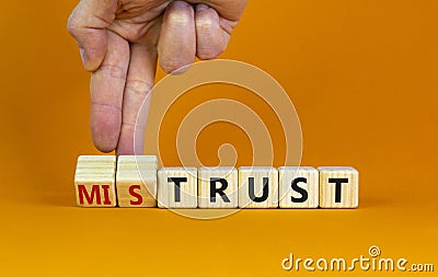 Mistrust or trust symbol. Businessman turns wooden cubes, changes words `mistrust` to `trust`. Beautiful orange table, orange Stock Photo