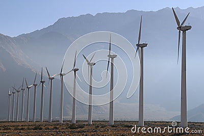 Misty afternoon desert mountains row tall wind turbines Stock Photo