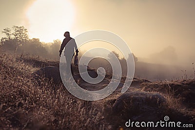 A misty morning by the lake. Silhouette of man walking away. Stock Photo