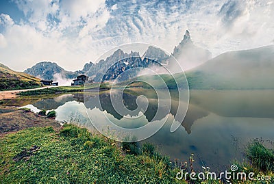 Misty morning view of Baita Segantini mountain refuge with Cimon della Pala peak. Exciting summer scene of Dolomiti Alps, Rolle Stock Photo