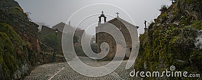 Misty morning view of church and cobblestone street in Monsanto. Stock Photo