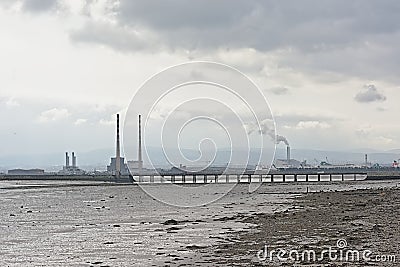 Misty view from across the water on Poolberg peninsula, with the chimneys of the power generation station , view from the beach Editorial Stock Photo