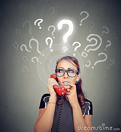 Misunderstanding and distant call. Upset worried confused woman talking on a phone has many questions Stock Photo