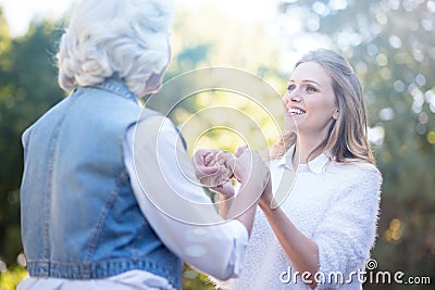 Kind young woman holding hands with grandmother in the park Stock Photo