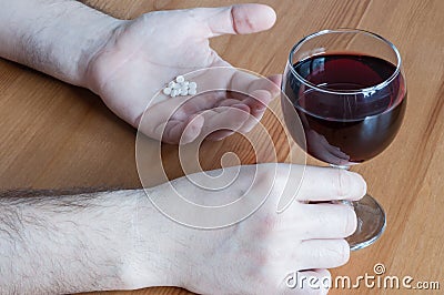 Mix alcohol with pills antibiotics red wine glass white hand table closeup concept combine Stock Photo