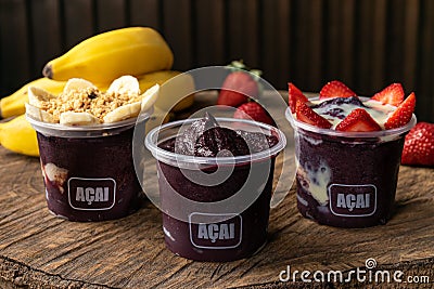 Mix of Delicious Brazilian AÃ§aÃ­ Cream, in a plastic Cup With a variety of Toppings, in a rustic wooden background. Summer acai Editorial Stock Photo