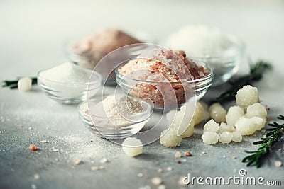 Mix of different salt types on grey concrete background. Sea salts, black and pink Himalayan salt crystals, powder Stock Photo