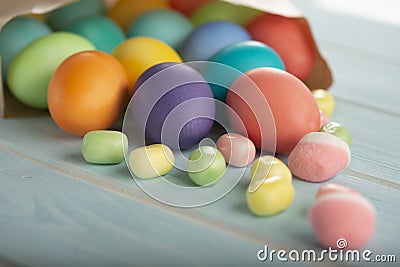 A mix of Easter bright dyed chicken eggs in a paper bag on a table Stock Photo
