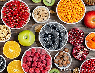 Mix of fresh berries, nuts and fruits. Healthy food contains a lot of vitamins and useful trace elements. Brown wooden background Stock Photo