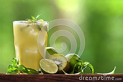 Mixed apple,kiwi and lime juice in glass with sliced lime, mint and kiwi on wood and nature Stock Photo