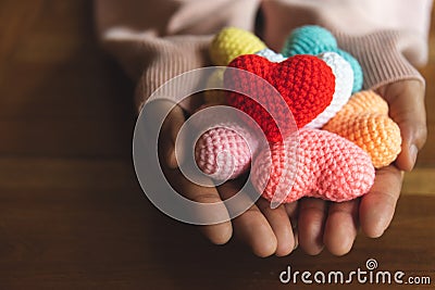 Mixed colors yarn heart on giving hands. Close up of colorful ha Stock Photo