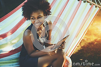 Mixed curly teenage female with digital tablet in hammock Stock Photo