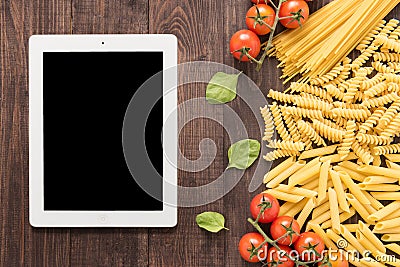 Mixed dried pasta selection and tablet on wooden background Stock Photo