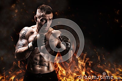 Mixed martial artist posing against the backdrop of fire and smoke. Concept of mma, ufc, thai boxing, classic boxing Stock Photo