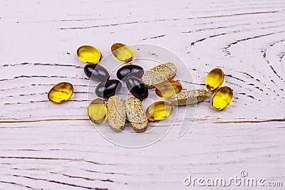 Mixed natural food supplement pills, omega 3, multivitamin capsules on white wooden table Stock Photo