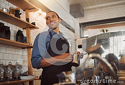 Mixed race barista steaming milk for coffee. Bistro worker frothing milk for a cup of coffee. Coffeeshop assistant Stock Photo