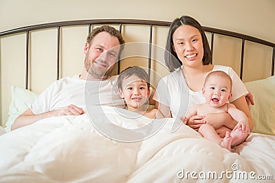 Mixed Race Chinese and Caucasian Baby Boys Laying In Bed with Their Father and Mother Stock Photo