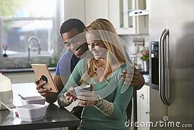 Mixed race couple looking at a tablet computer together in kitchen Stock Photo