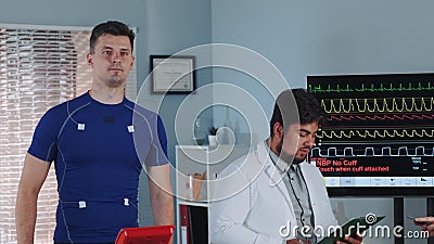 Mixed race doctor reading something while athlete treadmill testing on racetrack Stock Photo