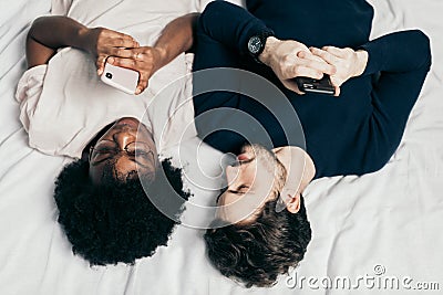 Mixed race family couple chat with friends lying in bed, dressed casual Stock Photo