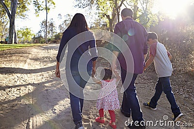 Mixed race family walking on rural path, backlit back view Stock Photo