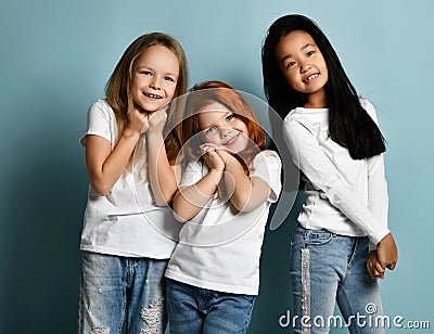 Mixed race international kids emotional girls in jeans and white t-shirts stand together melting feeling touched love Stock Photo
