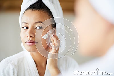 Mixed Race Woman Applying Face Cream Stock Photo