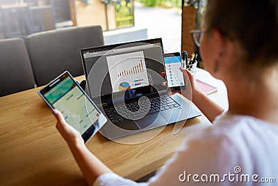 Mixed race woman in glasses working with multiple electronic internet devices. Freelancer businesswoman has tablet and Stock Photo