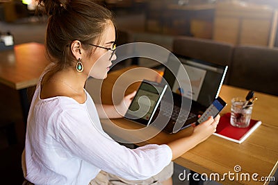 Mixed race woman in glasses working with multiple electronic internet devices. Freelancer businesswoman has tablet and Stock Photo