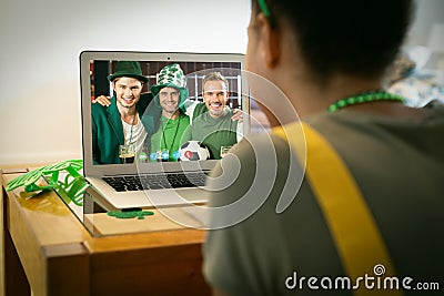 Mixed race woman having st patrick's day video call with three male friends on laptop at home Stock Photo