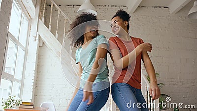 Mixed race young beautiful girls dancing on a bed together having fun leisure in bedroom at home Stock Photo