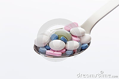 Mixed tablets in spoon against white background Stock Photo