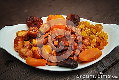 Mixed turkish nuts walnuts, raisins, dried apricots, almonds, hazelnuts. Assorted nuts and dried fruits in white plate. Stock Photo