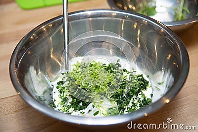 mixing chopped parsley, lime zest and sour cream in a metal bowl Stock Photo