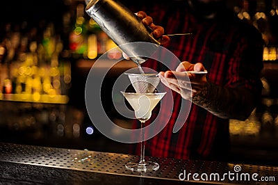 Mixologist pouring fresh and sour drink into a cocktail glass Stock Photo