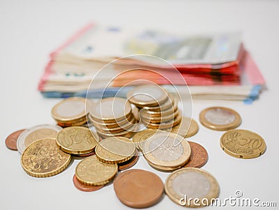 Mixture of Euro coins and banknotes lying on a white desk. Notes and coins of various denominations. Stock Photo