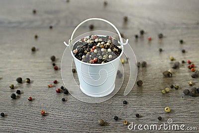 A mixture of pepper varieties with peas in the decorative little white bucket on the wooden background. Heap of various Stock Photo