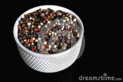 A mixture of pepper varieties with peas on the white plate on the black background. Heap of various pepper. Mix of red Stock Photo