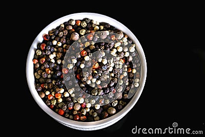 A mixture of pepper varieties with peas on the white plate on the black background. Heap of various pepper. Mix of red Stock Photo