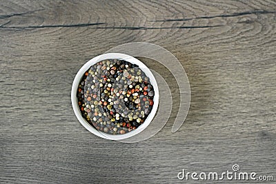 A mixture of pepper varieties with peas on the white plate on the wooden background. Heap of various pepper. Mix of red Stock Photo